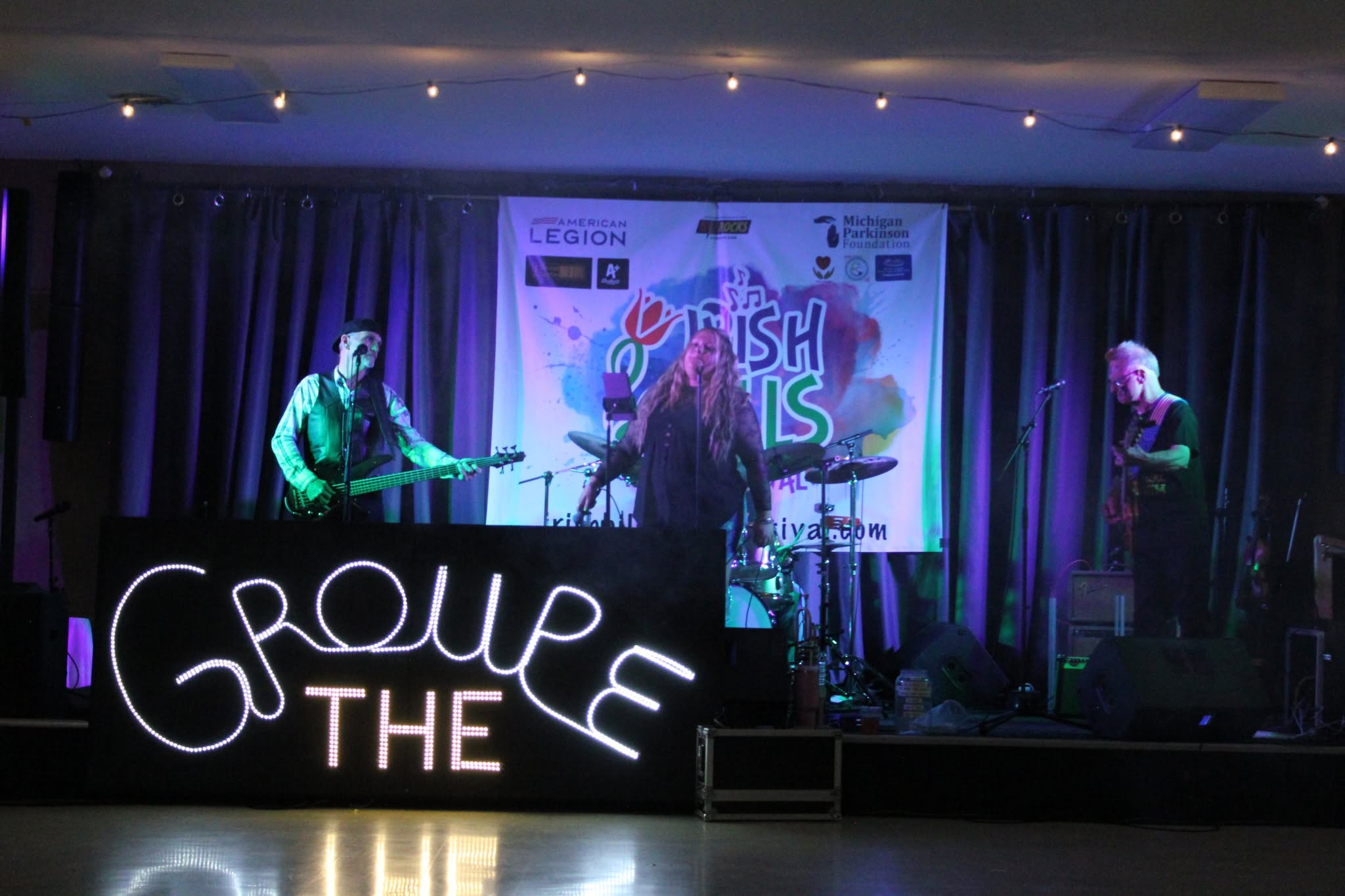 Groupe THE band performing with illuminated sign in front of stage