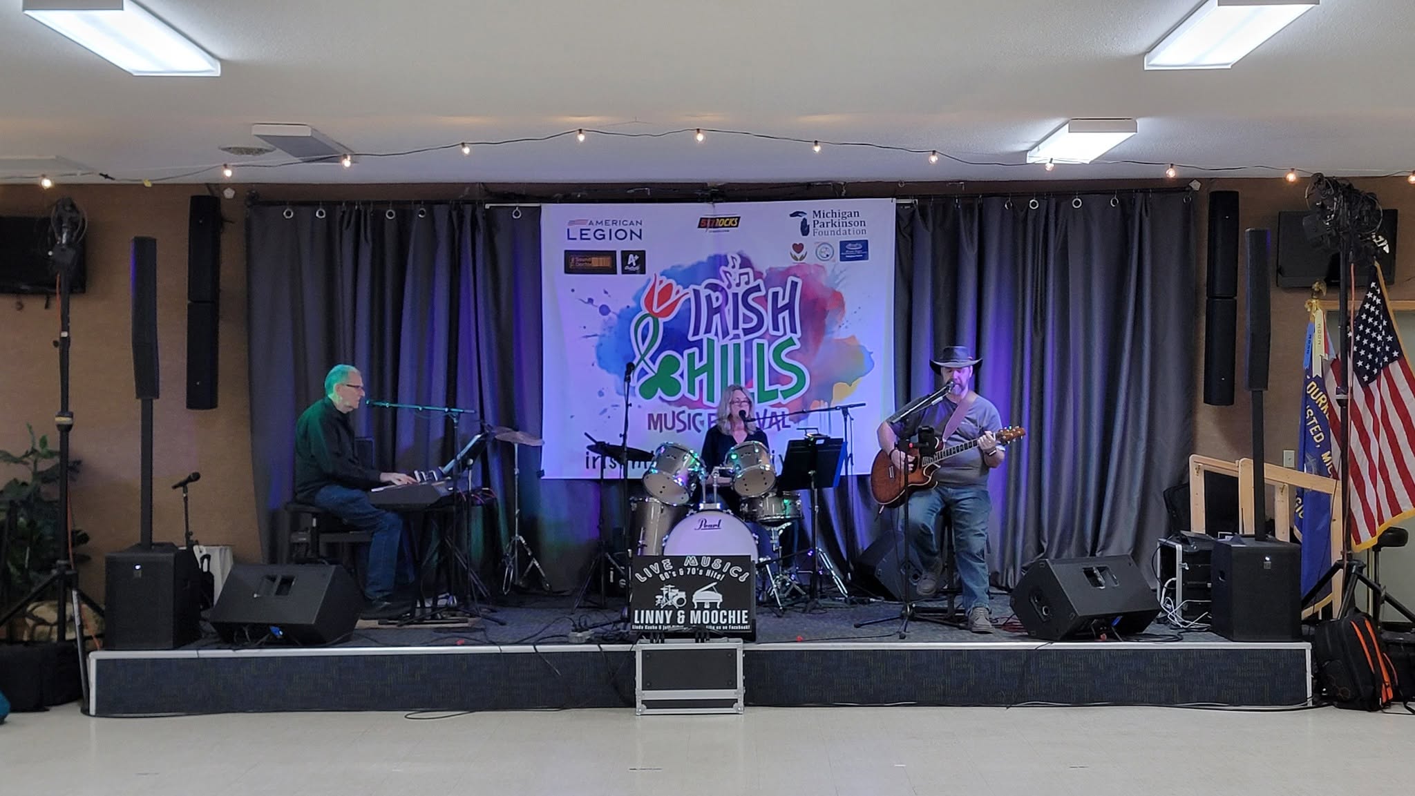 Linny & Moochie performing indoors with keyboard, drums, and acoustic guitar